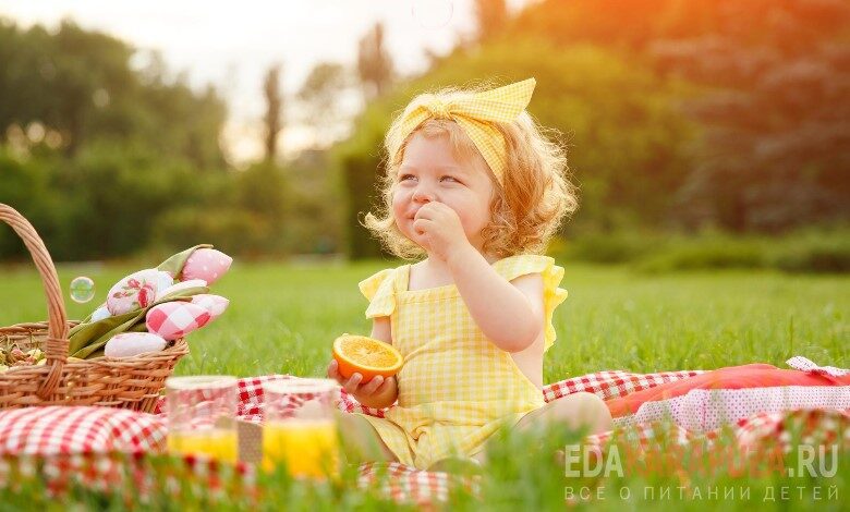 Маленькая девочка ест на природе